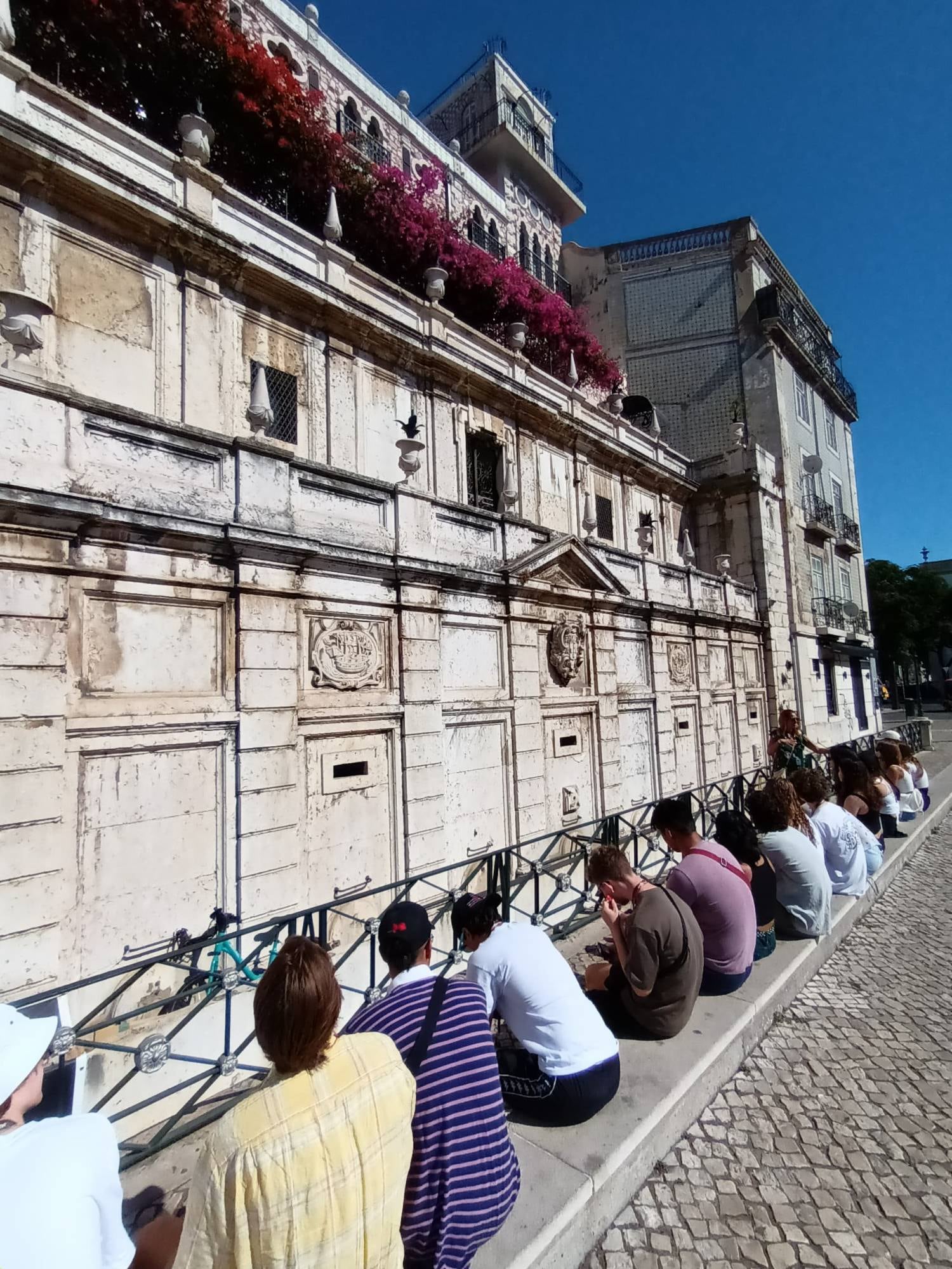 The NUin group on a curb in Lisbon, listening to a guide